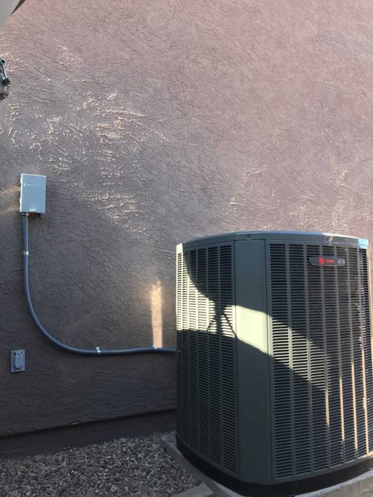 New outdoor heat pump and air conditioning unit installed against a Phoenix home