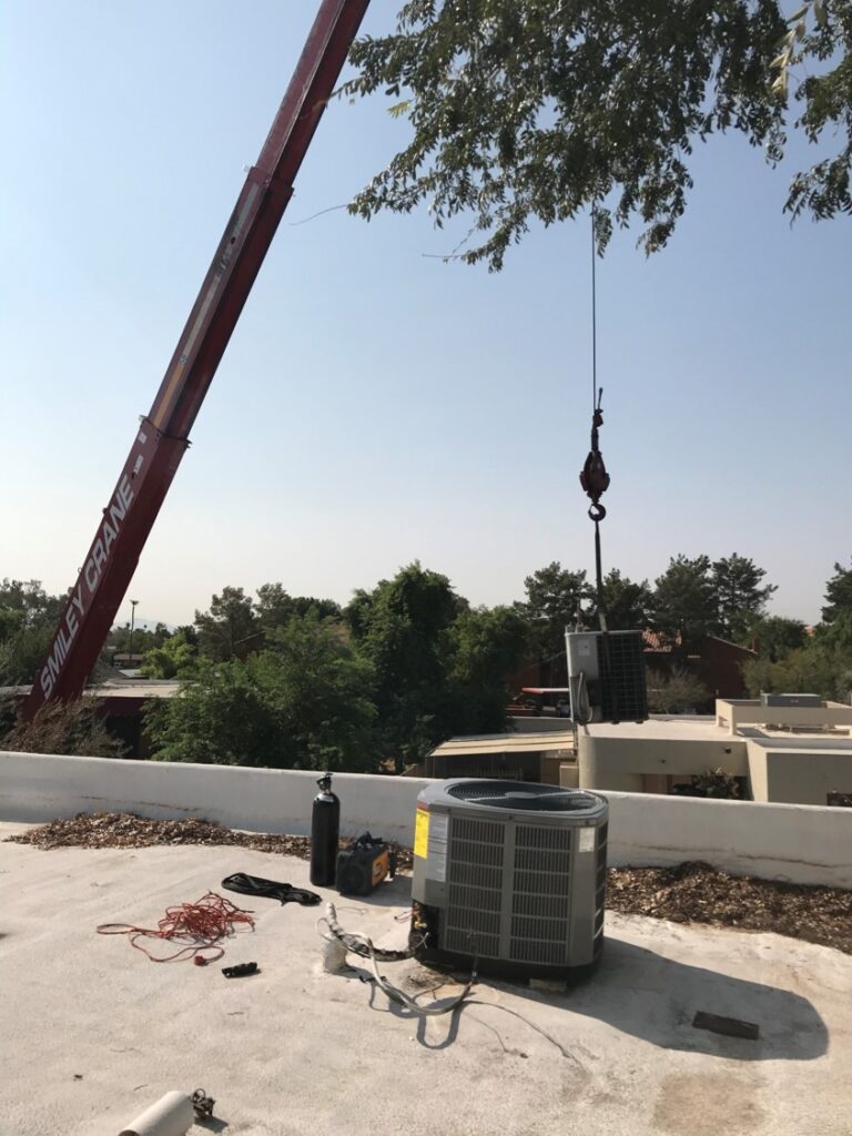 Crane lifting a new rooftop AC unit into place on a Phoenix building
