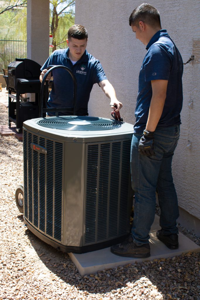 Two Legendary Energy technicians checking a newly installed Trane air conditioner