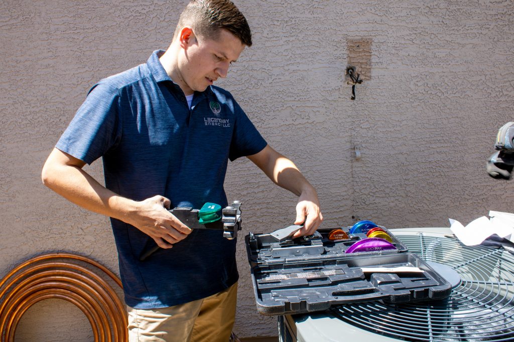 Legendary Energy technician cutting copper tubing beside an open parts case during an AC repair