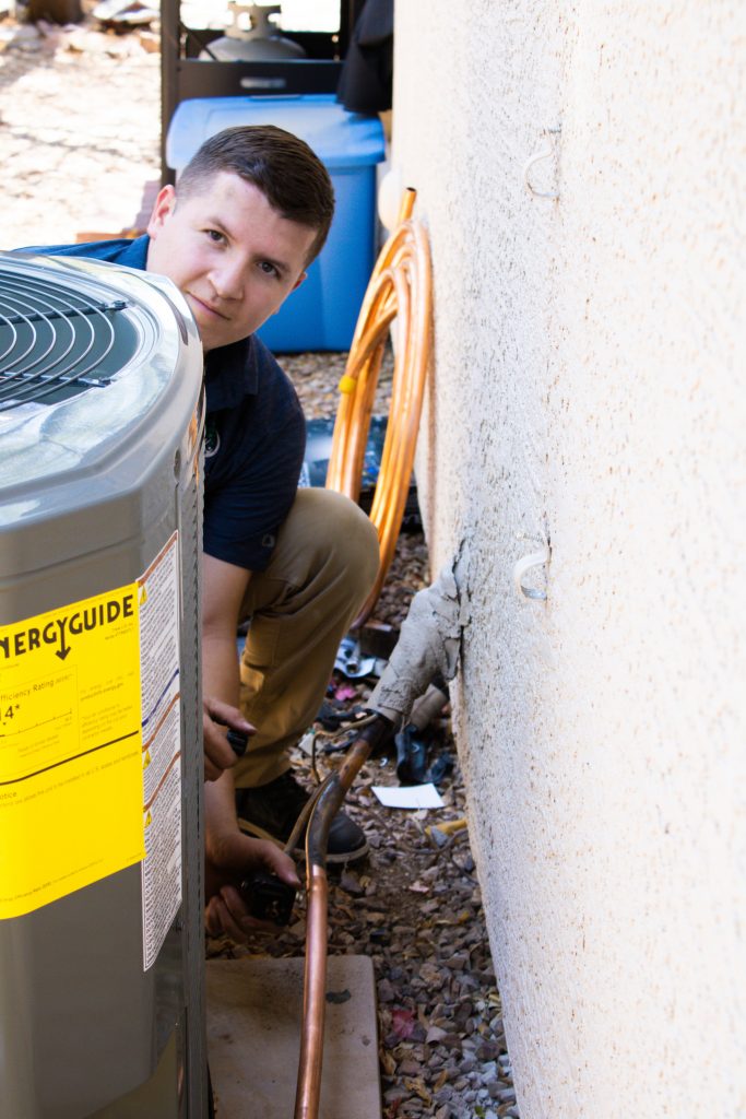 Smiling Legendary Energy technician beside a newly serviced outdoor unit