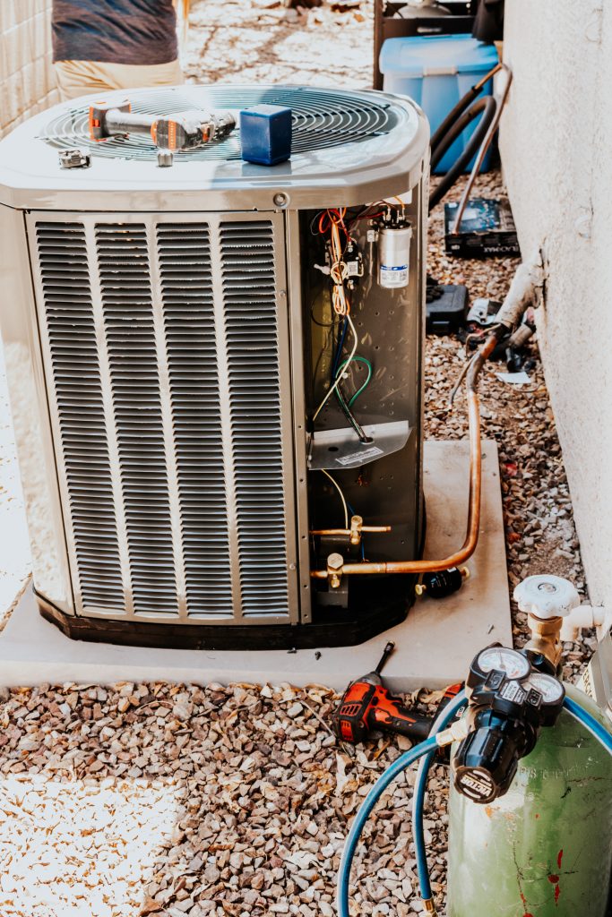 Outdoor heat pump unit with its service panel open and gauges connected