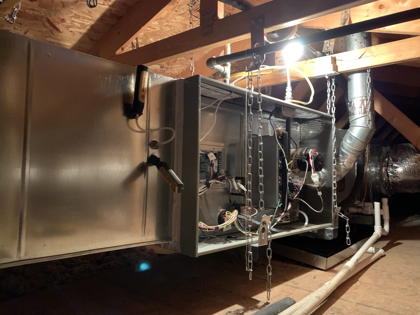 Hanging attic air handler with the access panel open and ducts connected